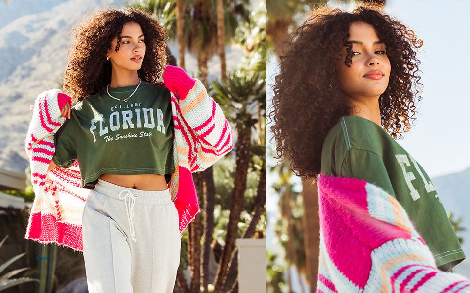 Women's Graphic Tees - A gal wearing a green graphic tee under a pink and white striped cardigan with a pair of grey sweatpants