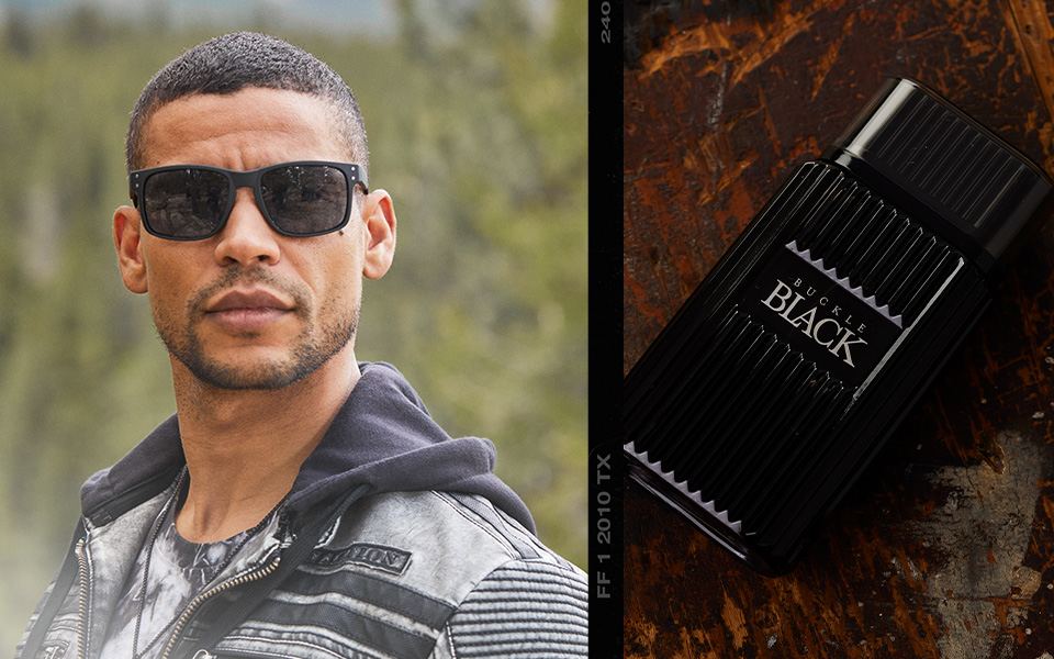 Men's Accessories - A guy wearing a pair of black sunglasses. A bottle of Buckle Black cologne