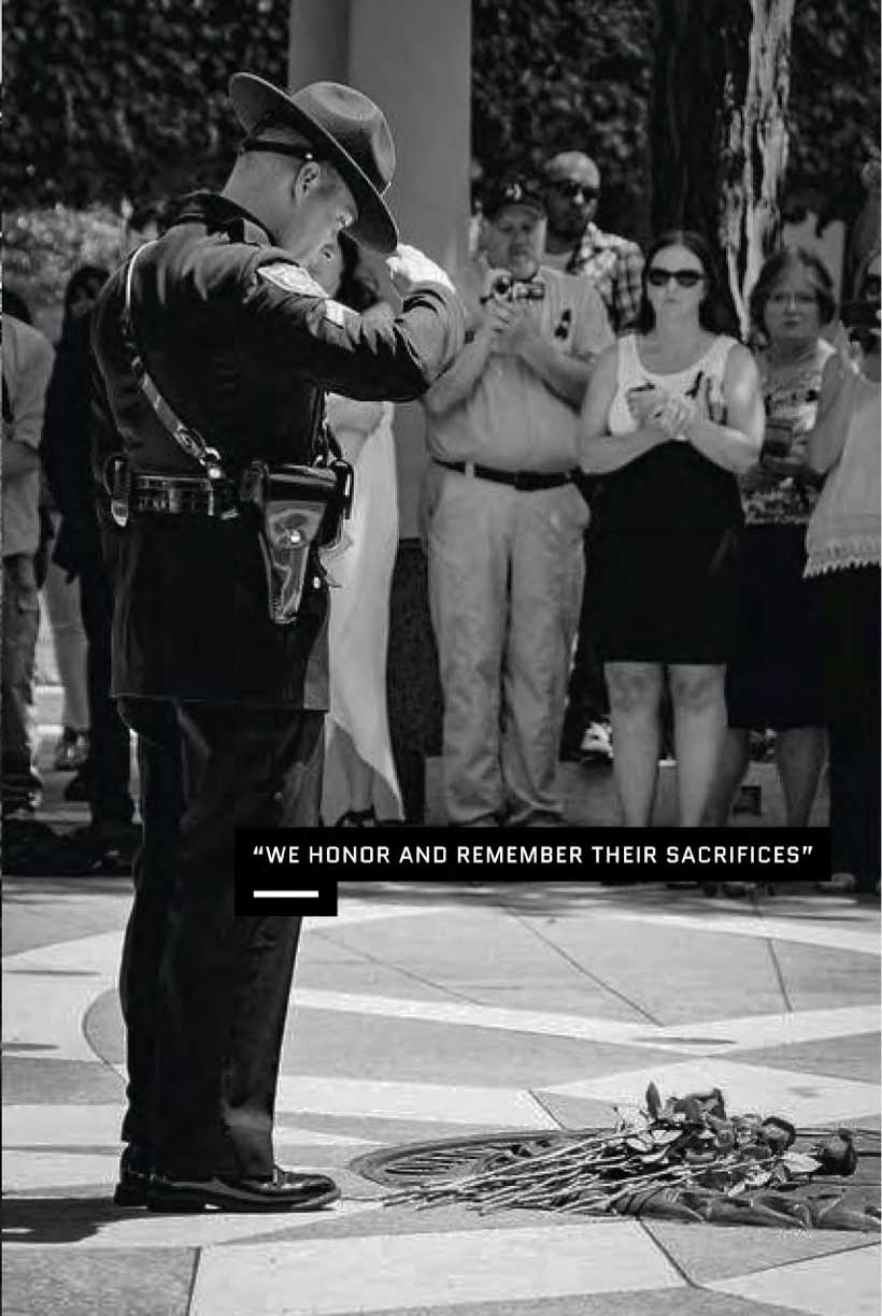 A police officer saluting a grave site while people are looking on