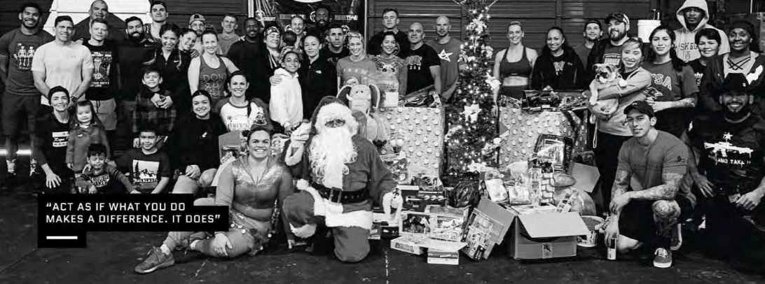 A group of people surrounding a Santa Claus, Christmas tree and presents